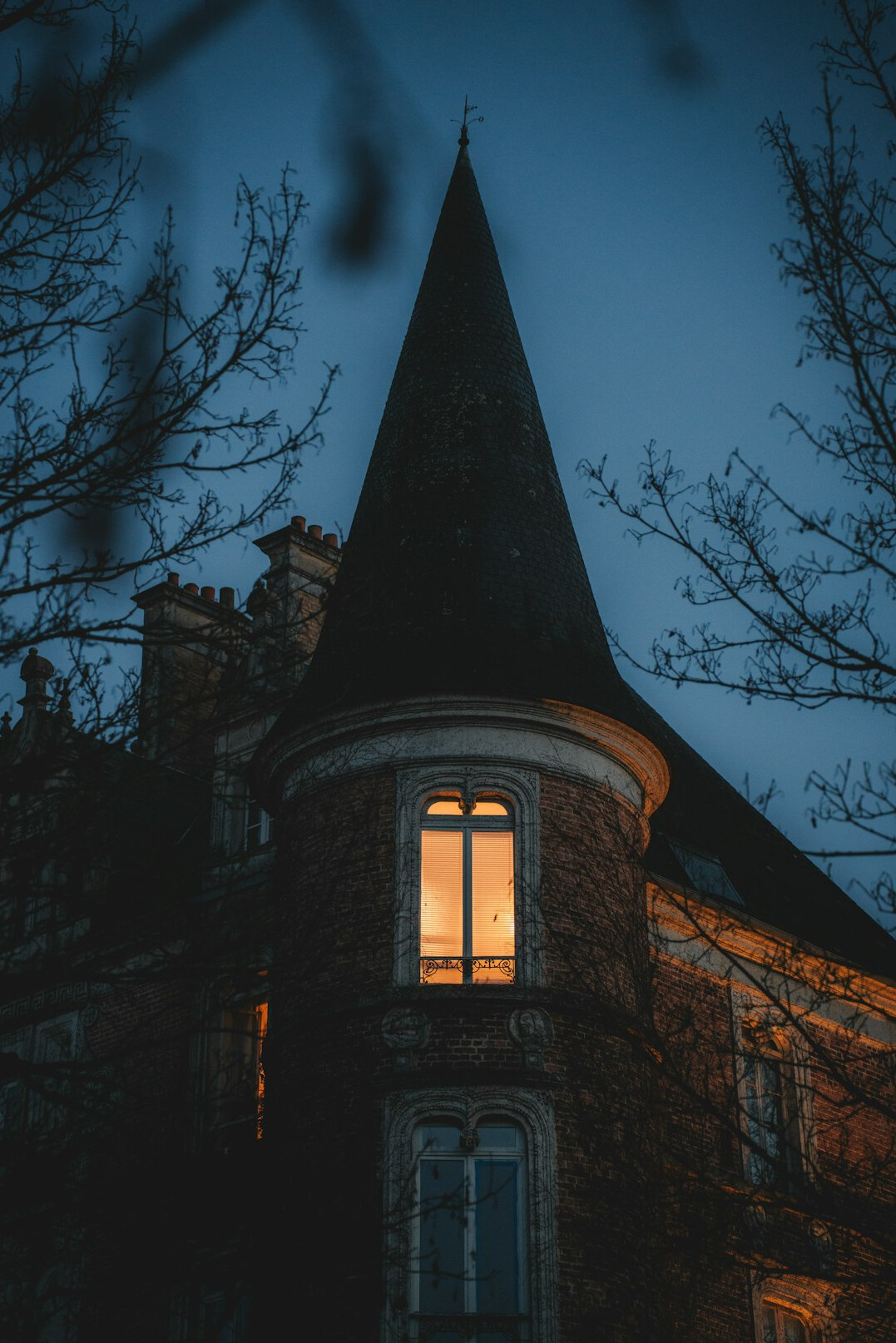 Old stone mansion silhouetted at dusk with dim lit windows