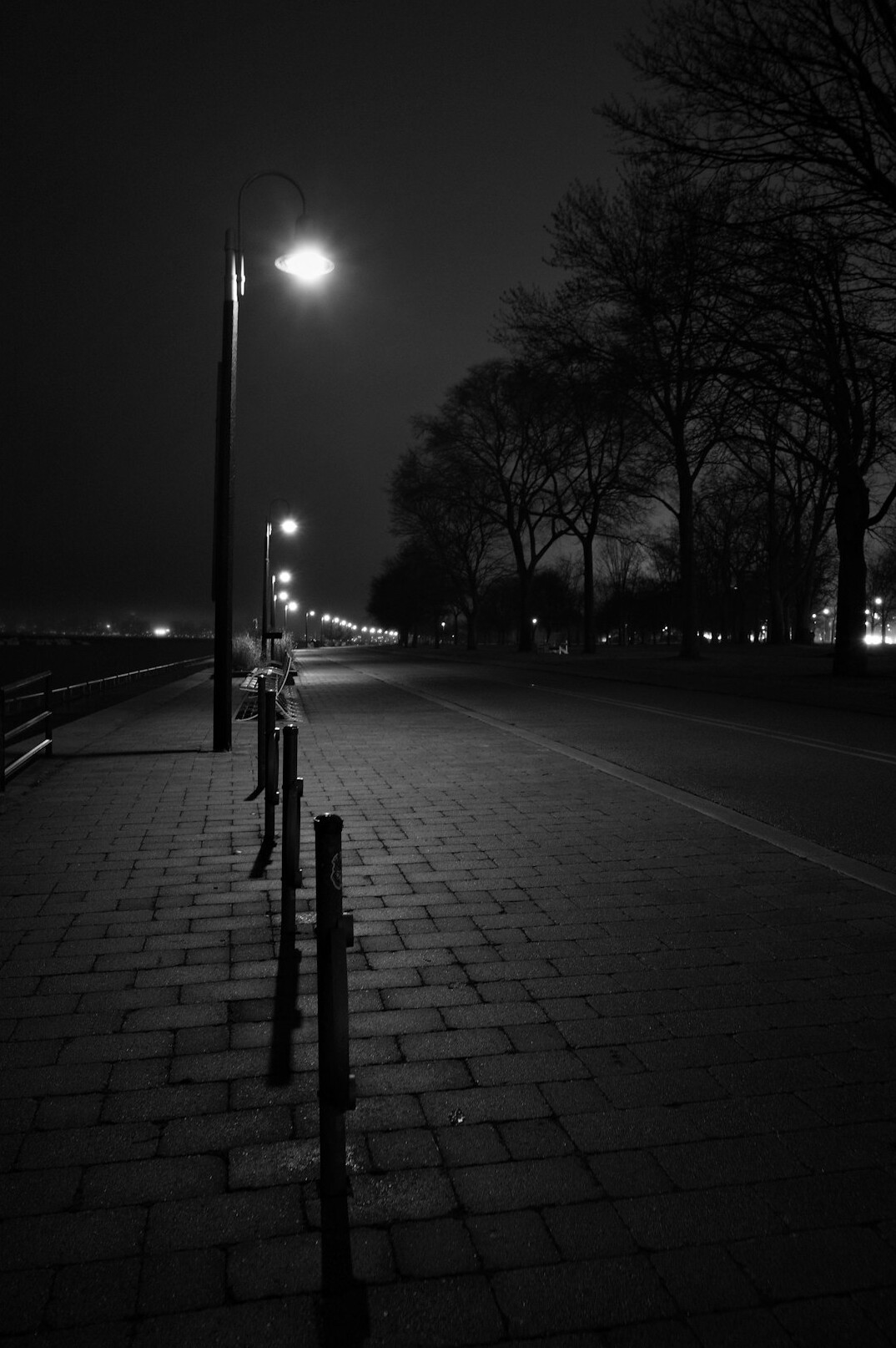 Foggy empty street at night lit by a single street lamp